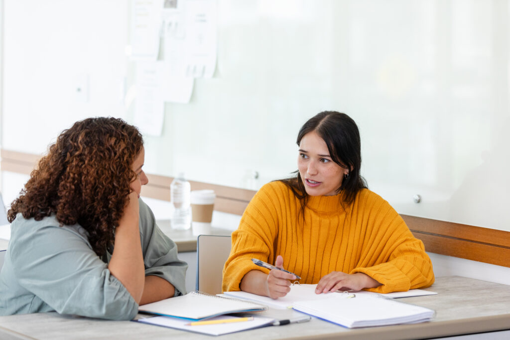 Female teacher listens as female student struggles with concepts