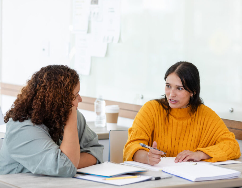 Female teacher listens as female student struggles with concepts